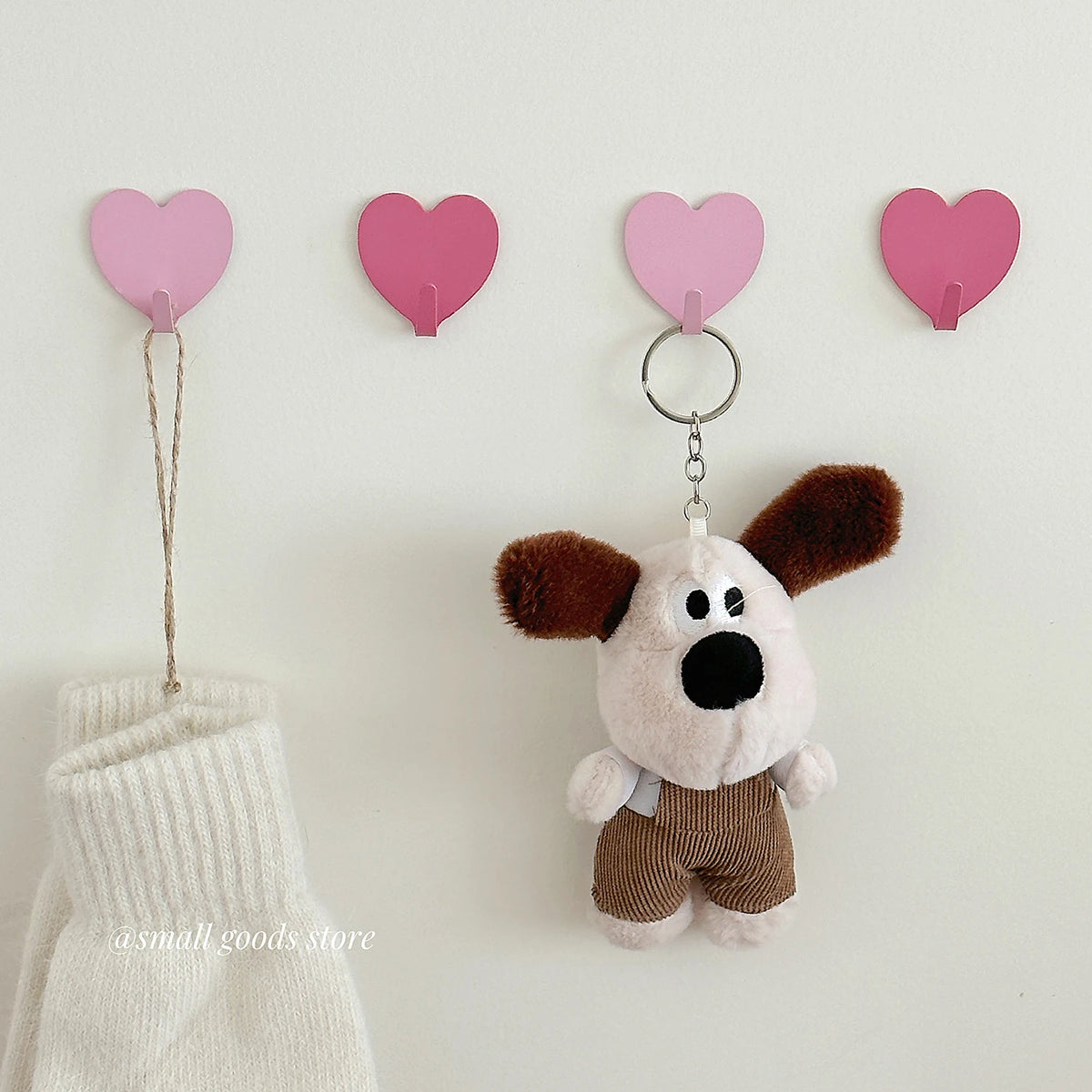 A set of pink heart-shaped adhesive wall hooks featuring a cute brown and white stuffed animal.