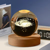 A dark glass crystal ball with a glowing interior rests on a wooden base.