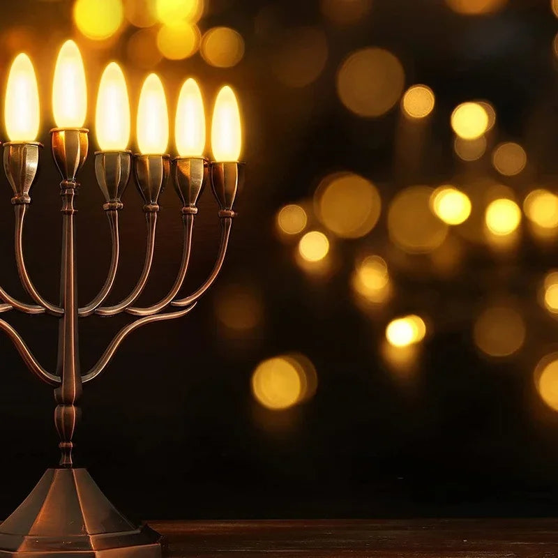 A brass candelabra with ten glowing LED candle bulbs illuminating a dark background with bokeh lights.
