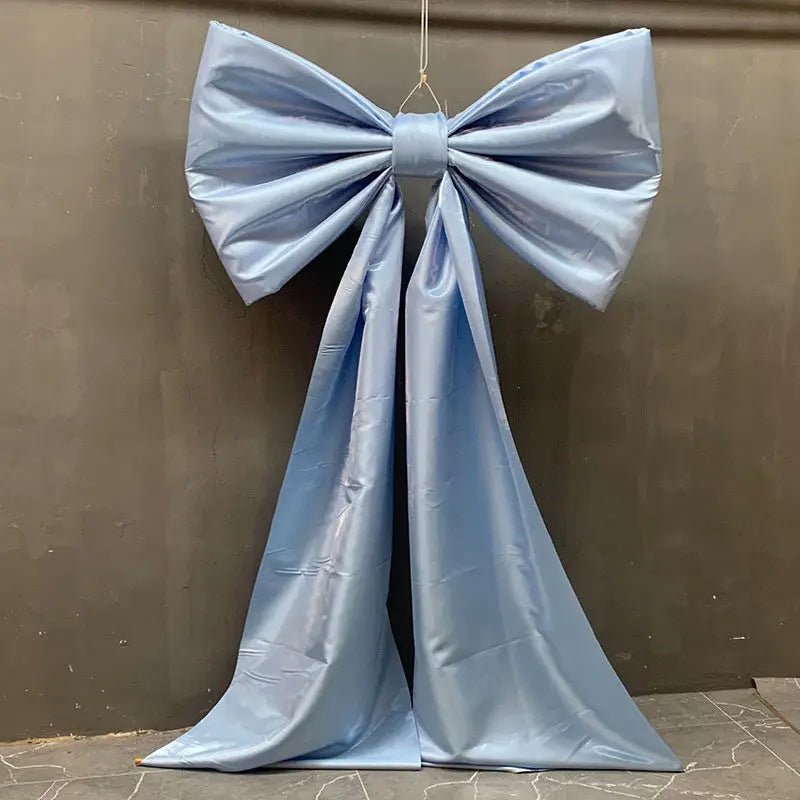 A light blue satin bow with long tulle drapes displayed against a dark gray background.