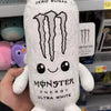 A white monster energy drink can shaped soft plush toy is held in a hand.