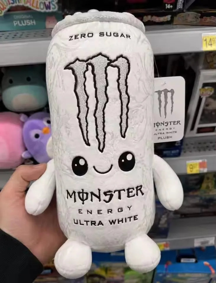 A white monster energy drink can shaped soft plush toy is held in a hand.