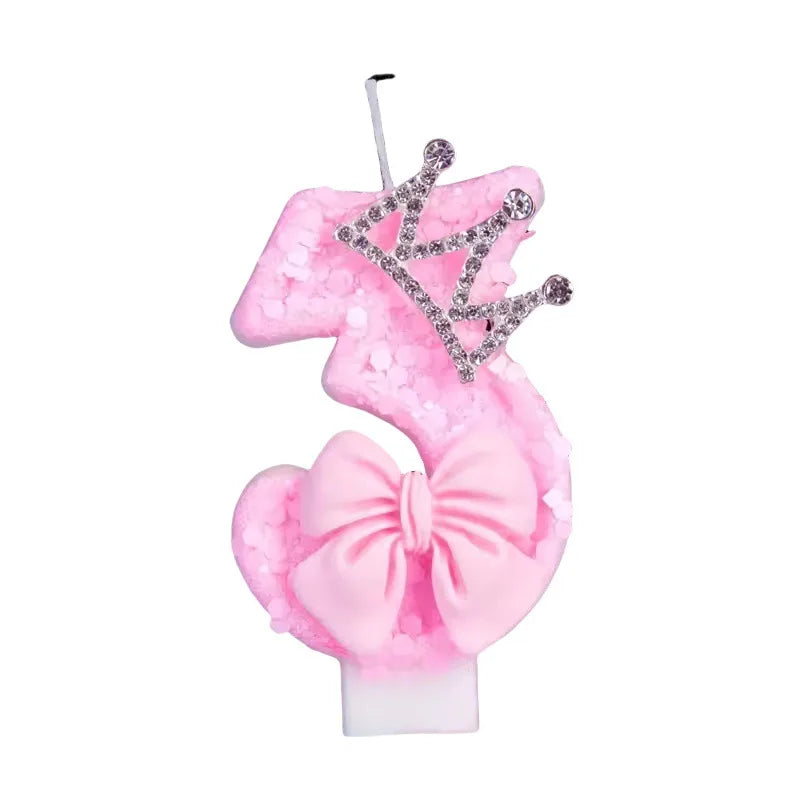 Pink glittery candle shaped like the number three with a crown topper