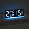 A digital alarm clock displaying 20:15 with blue light on, resting on a white surface.