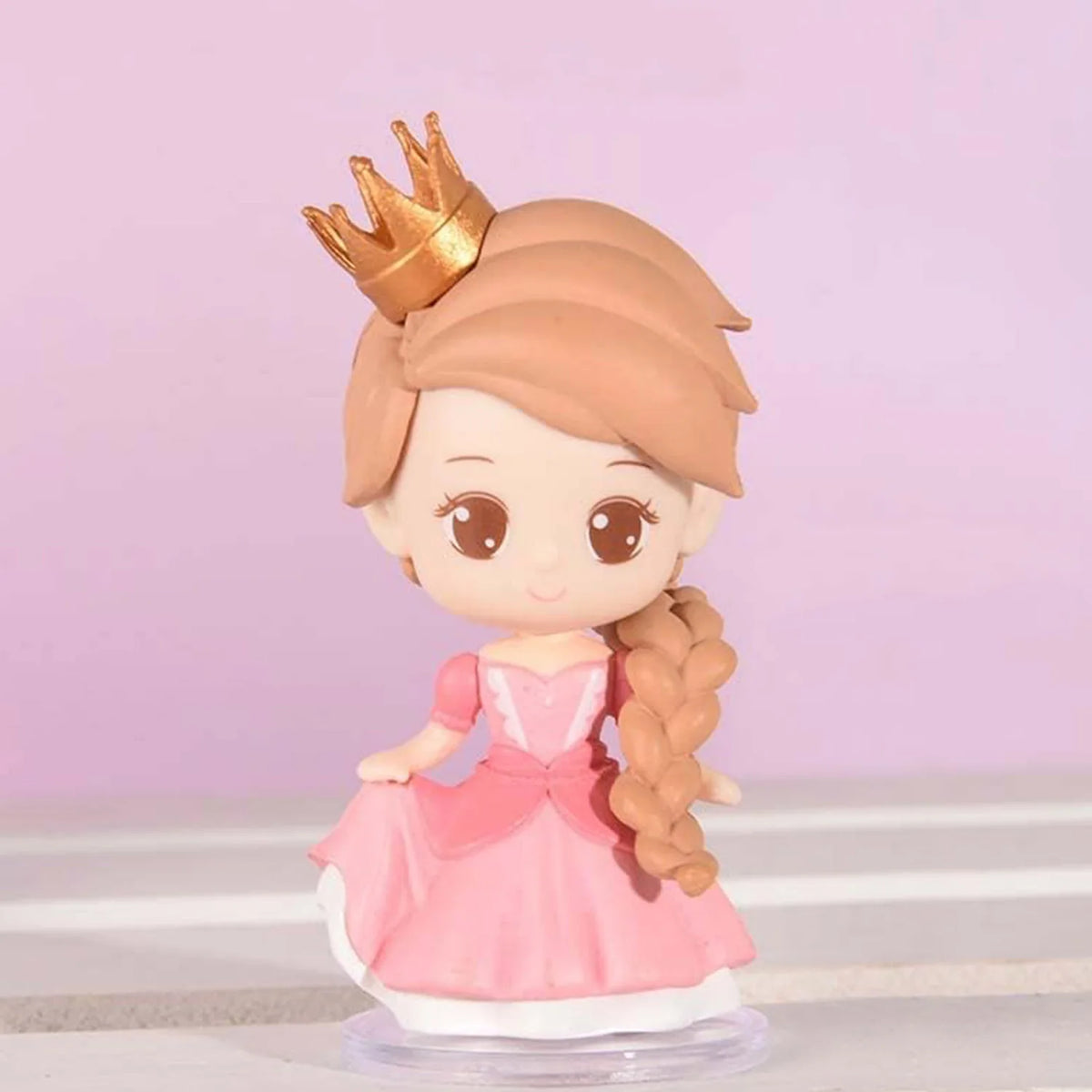 A figurine of a princess with a gold crown, wearing a pink dress and long brown hair, standing on a clear base.