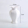 White ceramic vase with a flared rim and floral relief detailing, shown in a side profile.