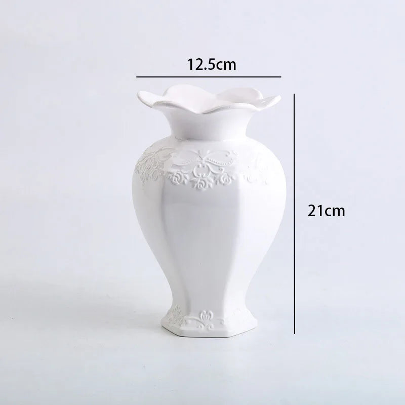 White ceramic vase with a flared rim and floral relief detailing, shown in a side profile.