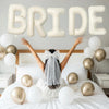 A bridal theme featuring white and gold balloons decorating a bed with a bride raising her arms.