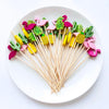 A plate of colorful pearl-tipped bamboo cocktail picks featuring pink, green, and yellow designs.