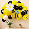 A yellow and black balloon arch set featuring bees and white daisies arranged on a table.
