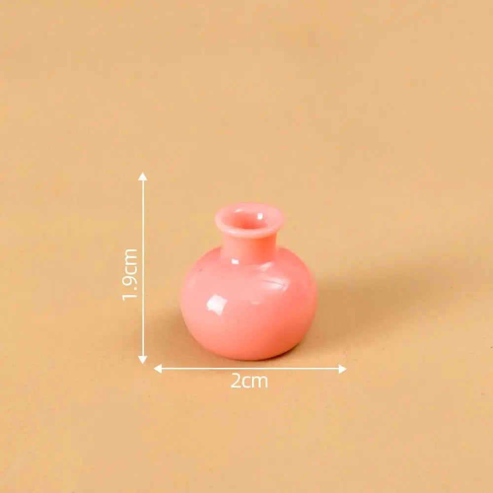 A small, round, pink resin vase with a narrow opening is shown against a neutral background.