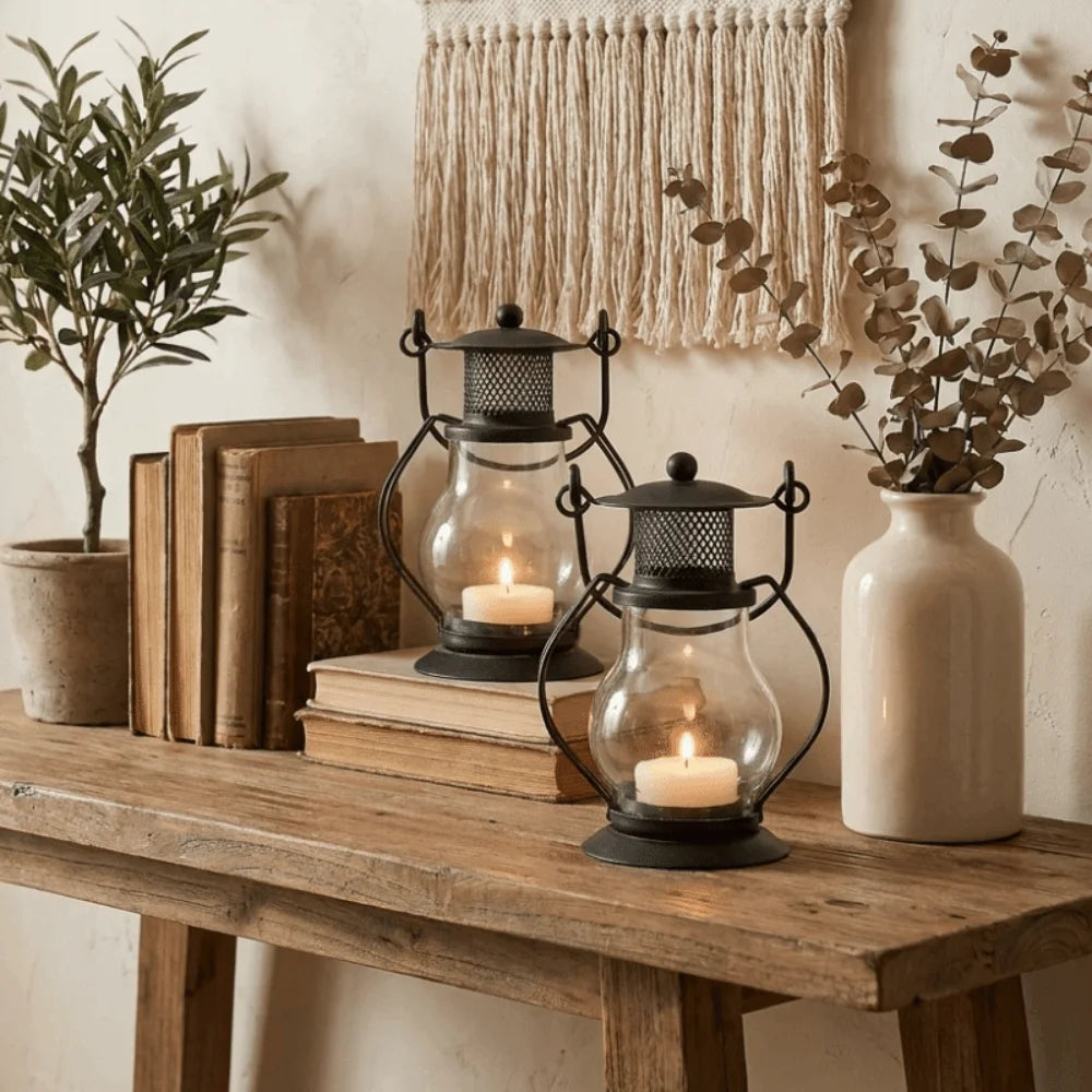 A collection of decorative metal candlestick lanterns and potted greenery displayed on a wooden table.