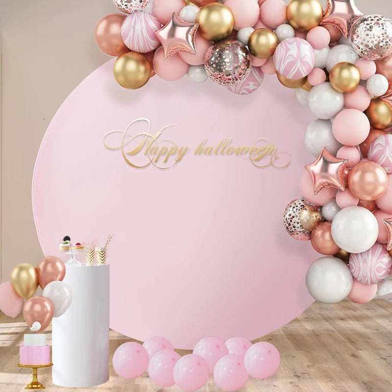 A pink and gold balloon arch backdrop with a large text banner that reads Happy Halloween