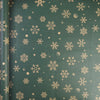 Roll of festive Christmas kraft wrapping paper featuring gold snowflake patterns on a dark green background.