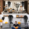 A decorative display featuring artificial black vine hanging plants and orange accents indoors.