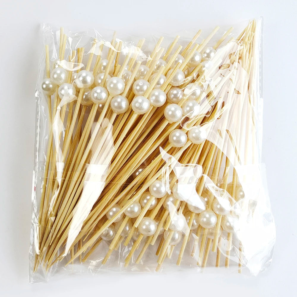 A clear plastic bag filled with numerous bamboo cocktail picks tipped with white pearls.