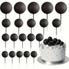 A collection of black and silver foam ball cake toppers on sticks for party decorations