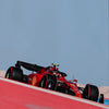 A red Formula 1 car is shown in profile on a track wall, set against a clear blue sky.