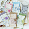 A collection of vintage old English manuscript decor paper in various shades and designs laid out on a white fabric.
