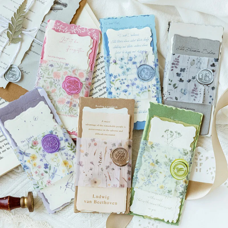 A collection of vintage old English manuscript decor paper in various shades and designs laid out on a white fabric.
