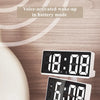A white digital alarm clock displaying 18:08 and 6:08, shown in a close-up on a wooden surface.