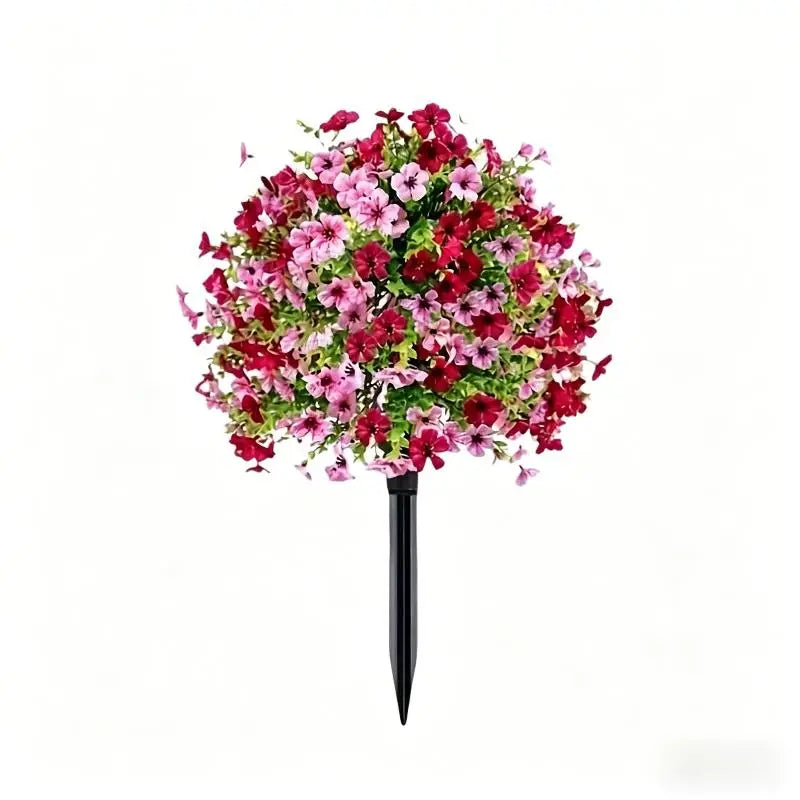 A bouquet of lifelike artificial petunias in shades of pink and deep red, mounted on a black stake.