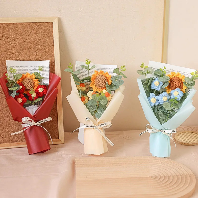 A bouquet of handcrafted crochet sunflowers and blue flowers wrapped in light blue paper and tied with a white ribbon.