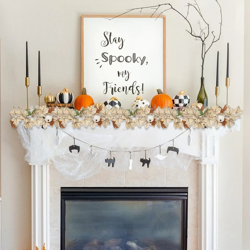A white fireplace mantel decorated with an artificial maple leaf garland, pumpkins, and a framed sign that reads Stay Spooky 