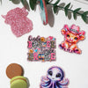 Pink glitter acrylic charms featuring a bunny, a cowboy hat, and a purple octopus for DIY crafts