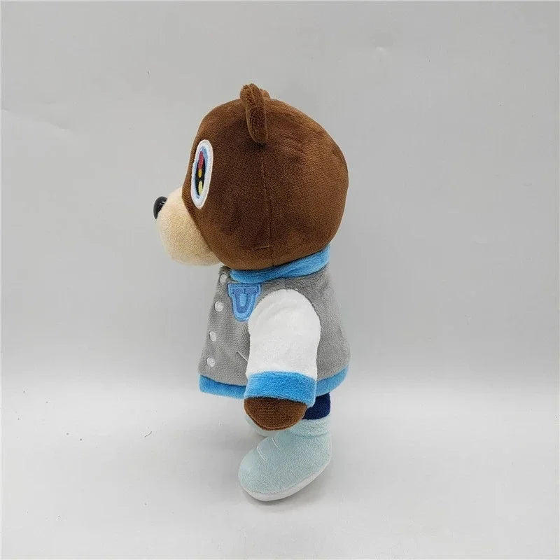 A brown bear plush toy with a blue collar and gray and white clothing, standing against a light background.