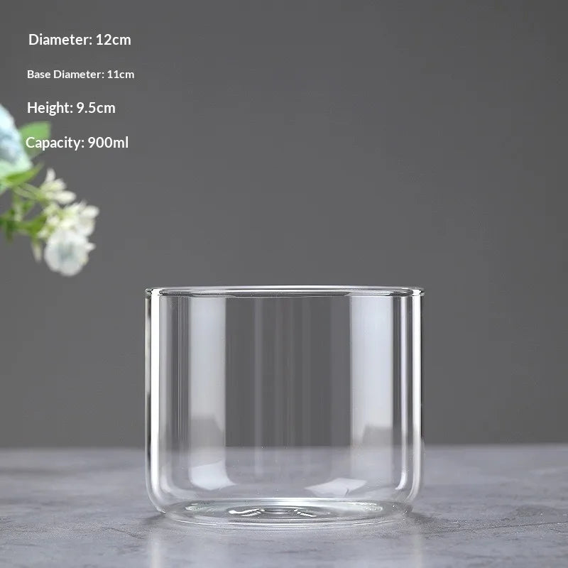 A clear glass cylindrical vase with a wide opening sits on a gray surface.