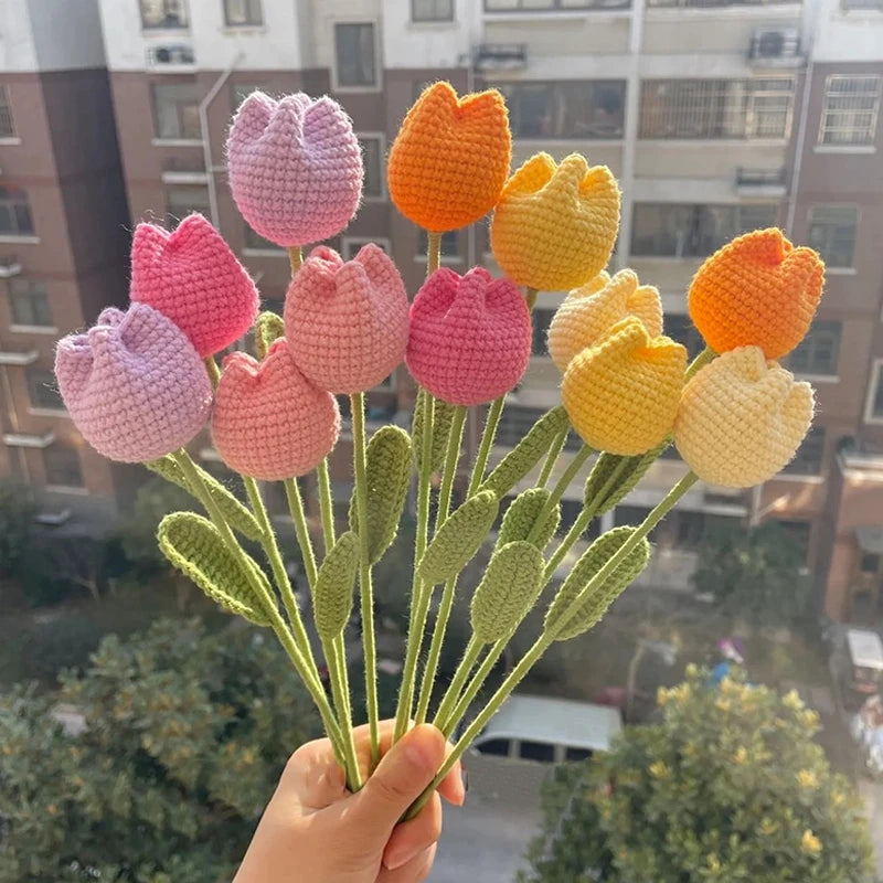 A bouquet of handmade crochet tulips in shades of pink and orange, displayed against an outdoor background.