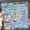 A clear plastic sheet containing square panels of pink and blue shimmer sequins for party decor.