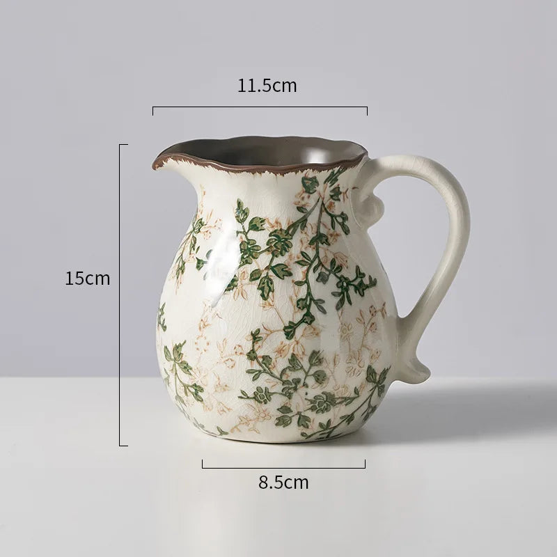 A rustic ceramic milk pitcher with a cracked glaze and pastoral floral design, shown against a light gray background.