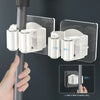 A hand is shown using a wrapped clamping device to attach or detach a mop and broom holder from a vertical pole.
