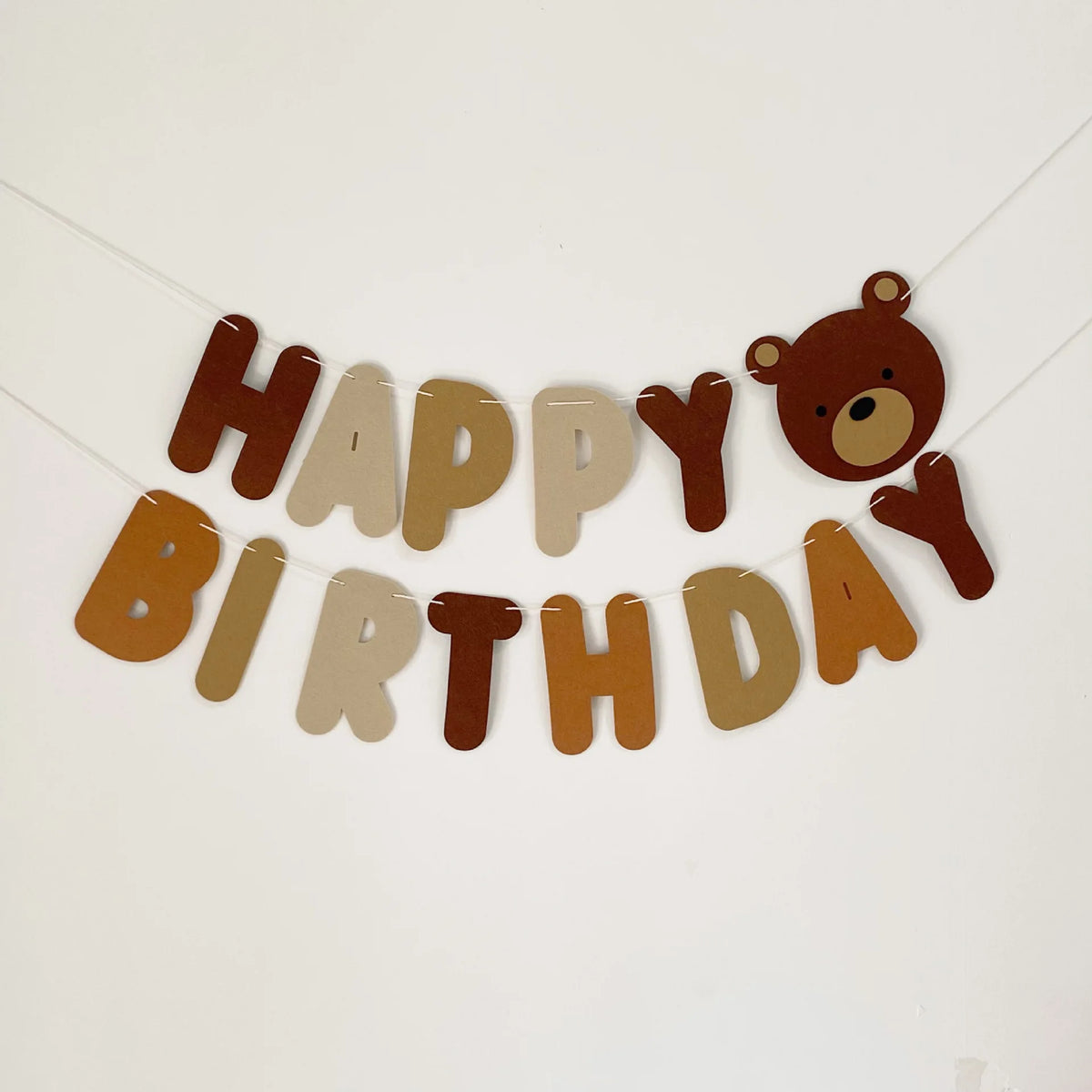 A banner spelling out Happy Birthday made of wooden letters and a teddy bear cutout.