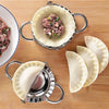 Stainless steel dumpling maker with crimped edge holding a portion of pink meat filling and several dumplings.
