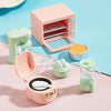 A set of pink and mint green kitchen appliance dollhouse accessories including a toaster, blender, and food container.