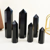 A set of black obsidian crystal obelisks or points standing upright on a white surface.