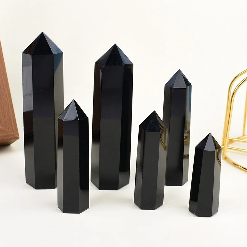 A set of black obsidian crystal obelisks or points standing upright on a white surface.
