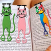 A close-up of a book featuring illustrations of three cats used as decorative bookmarks.