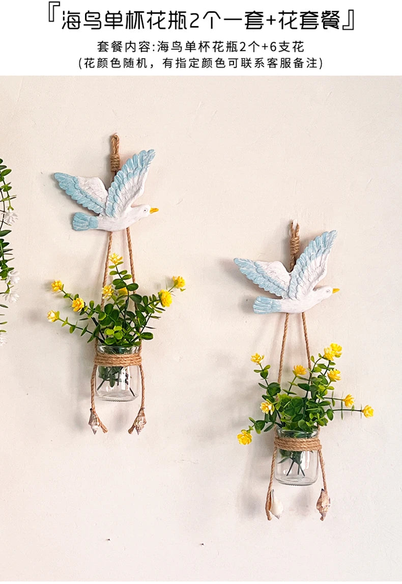 A decorative hanging display featuring white and blue bird-like figures with small potted yellow flowers.