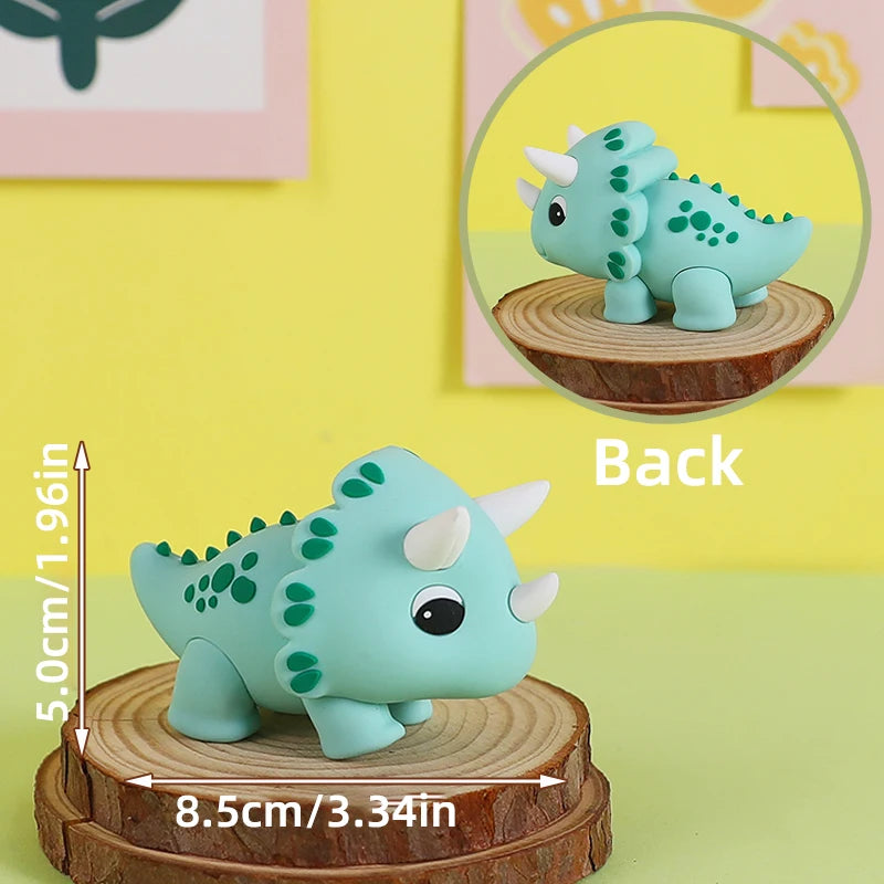 Topper de pastel de dinosaurio azul claro con cuerpo texturizado verde y cuernos blancos, visto desde atrás.
