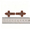 Deux petits pendentifs en bois en forme de croix sont montrés à côté d'une règle pour l'échelle.