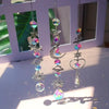 A silver pendant featuring a rainbow sun catcher design with various colored crystals and a moon charm.