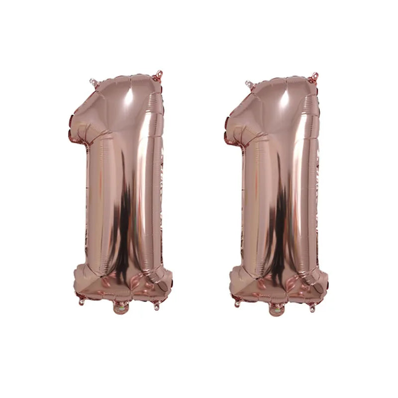 Two rose gold foil number balloons shaped like the number 1, used for birthday party decor.
