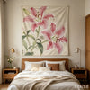 Pink lily tapestry featuring large floral print hanging above a wooden bed frame.