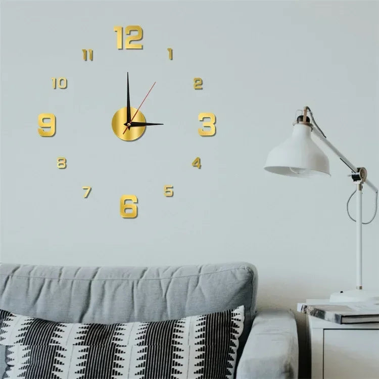 A modern wall clock with gold numbers and hands is displayed above a gray sofa.