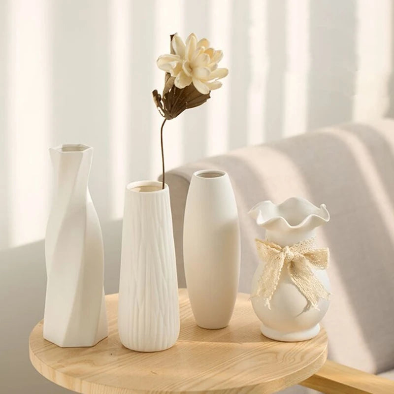 A collection of white ceramic bud vases and a dried flower displayed on a wooden surface.