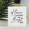 A white sign with black script that reads Home is where my Boys are and a small red heart.